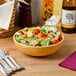 A Tuxton assorted color bowl filled with salad on a table.