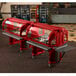 A red Cambro food cart with a red top holding buffet food.