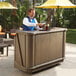 A man standing behind a Cambro portable bar serving a drink.