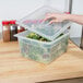 A hand using a Cambro translucent plastic lid to open a container of salad.