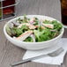 A Tuxton eggshell coupe bowl filled with salad with chicken and lettuce.