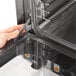 A hand opening the metal door of a Vollrath countertop convection oven.