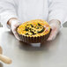 A person holding a quiche with a removable bottom in a Gobel fluted tart pan.