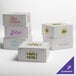 A group of white customizable cake boxes with different colored text designs.