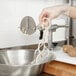 A person using a Nemco Spiral Fry Cutter to cut an onion