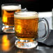 Two Anchor Hocking beer tasting mugs filled with beer on a table.