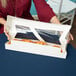 A woman holding a white auto-popup window bakery box filled with donuts.