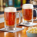 Two Libbey beer mugs filled with beer on a table.