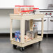 A beige Continental utility cart with containers of food on the shelves.