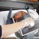 A person using a Hobart meat slicer to cut meat.