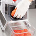 A person in gloves using a Vollrath Redco InstaSlice machine to cut tomatoes.