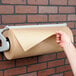 A hand holding a roll of Bagcraft Packaging natural freezer paper.