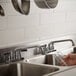 A hand holding a glass in an Advance Tabco drop-in sink.