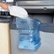 A person pouring ice into a blue Rubbermaid ice container.