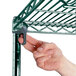 A hand attaching a Metroseal 3 wire shelf to a Metro Super Erecta wire shelving unit.