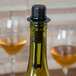 A bottle of wine with a black wine filter/pourer on it.