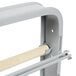 A gray metal rack with a wooden stick holding 6 rolls of paper.