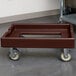 A dark brown plastic Cambro pizza dough box dolly.
