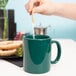 A person pouring tea into a Tuxton hunter green mug with a c-handle.