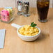 A Tuxton eggshell casserole bowl filled with macaroni and cheese on a table.