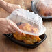 Two people holding plastic containers with chicken.