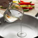 A person pouring Admiration Pure Vegetable Salad Oil into a pan of vegetables.