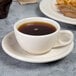 A Homer Laughlin ivory china cup filled with brown liquid on a table with food.