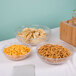 A table with a Cambro pebbled serving bowl of chips, a bowl of goldfish crackers, and a bowl of pretzels.