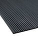 A close-up of a black rubber mat with deep grooves.