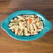 A turquoise Fiesta oval china baker filled with pasta and vegetables.