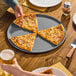 A 16-inch hard coat anodized aluminum coupe pizza pan holding three slices of pizza.