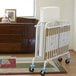 A white metal L.A. Baby folding crib with a mattress on it.