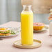 A Libbey glass bottle filled with orange juice on a table.