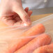 A person putting a bunch of carrots in a plastic slide seal bag.