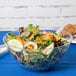 A clear Fineline plastic bowl filled with salad.