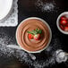 A white porcelain cake stand with a chocolate cake topped with strawberries.