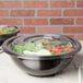 Two Fineline clear flat lids on salad bowls filled with salad.
