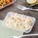 A white plastic rectangular tray holding a container of food with a fork and spoon.