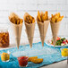 A table with paper cones of french fries on a Choice 4 Hole Acrylic Cone Holder.