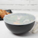 A Fineline clear plastic bowl with a flat lid on a table with food inside.