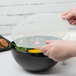 A person holding a Fineline clear plastic lid over a bowl of food.