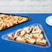 A clear Fineline triangular plastic tray with food on a table.