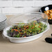 A salad in a Fineline clear plastic oval tray with a plastic dome lid.