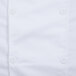 A close up of a white Mercer Culinary chef jacket with a white button with four holes.