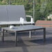 A Grosfillex aluminum cocktail table on an outdoor patio with wine glasses on it.