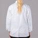 A woman wearing a white Mercer Culinary long sleeve chef jacket.