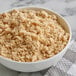 A bowl of light brown sugar on a table.