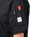 A person wearing a Mercer Culinary black short sleeve chef jacket with a pen in the pocket.