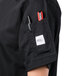 A person wearing a Mercer Culinary black chef jacket with a pen in the pocket.