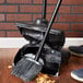 A Rubbermaid angled lobby broom and dustpan on a wood floor.